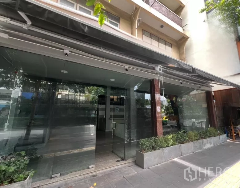 อาคารพาณิชย์ ให้เช่าในWatthana, Bangkok - ทางเข้าใต้กันสาดพร้อมประตูกระจกใสและกระบะต้นไม้ริมทางเท้า.