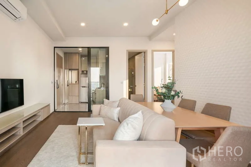 Condominium for rent - Neutral-toned living and dining area with wall-mounted TV and access to kitchen and bedrooms.