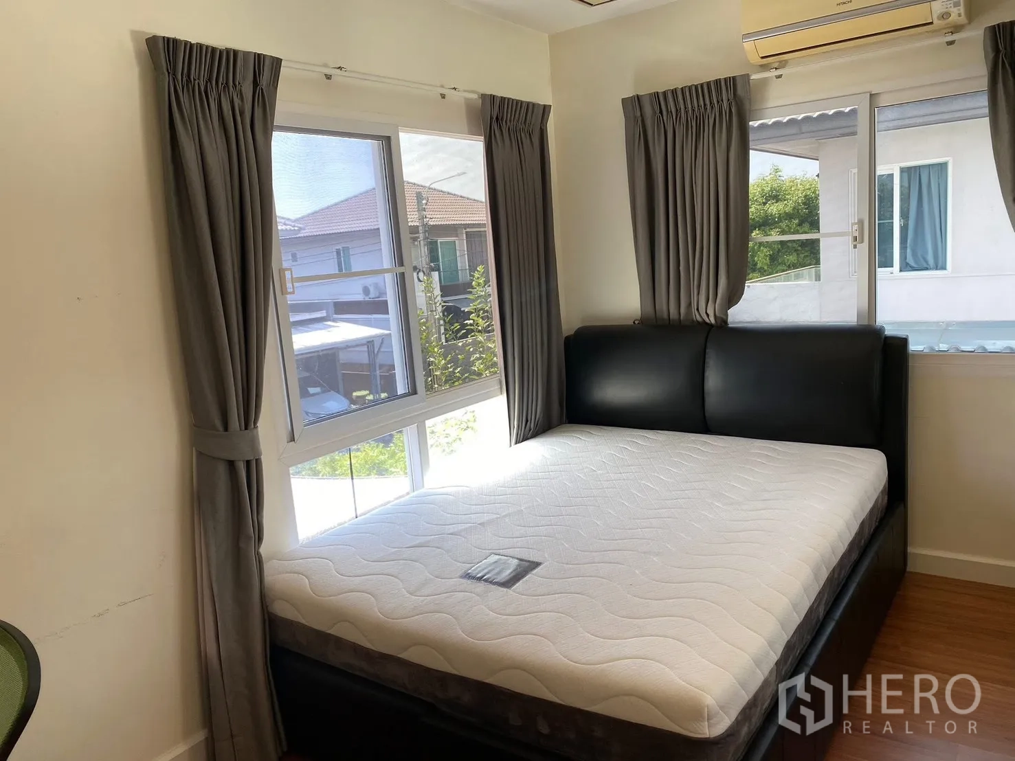 Detached House for rent in Prawet, Bangkok - Corner bedroom with large windows, curtains, and a bed.