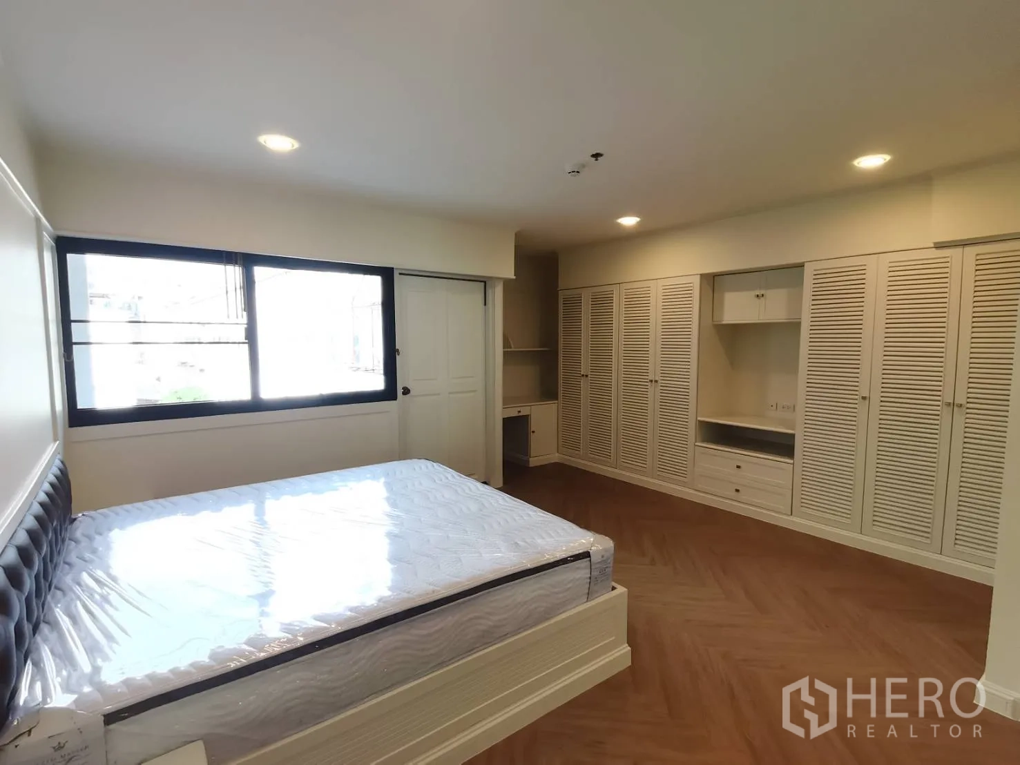 Condominium for rent in Watthana, Bangkok - Bedroom showcasing extensive built-in wardrobes and a bed by the window.