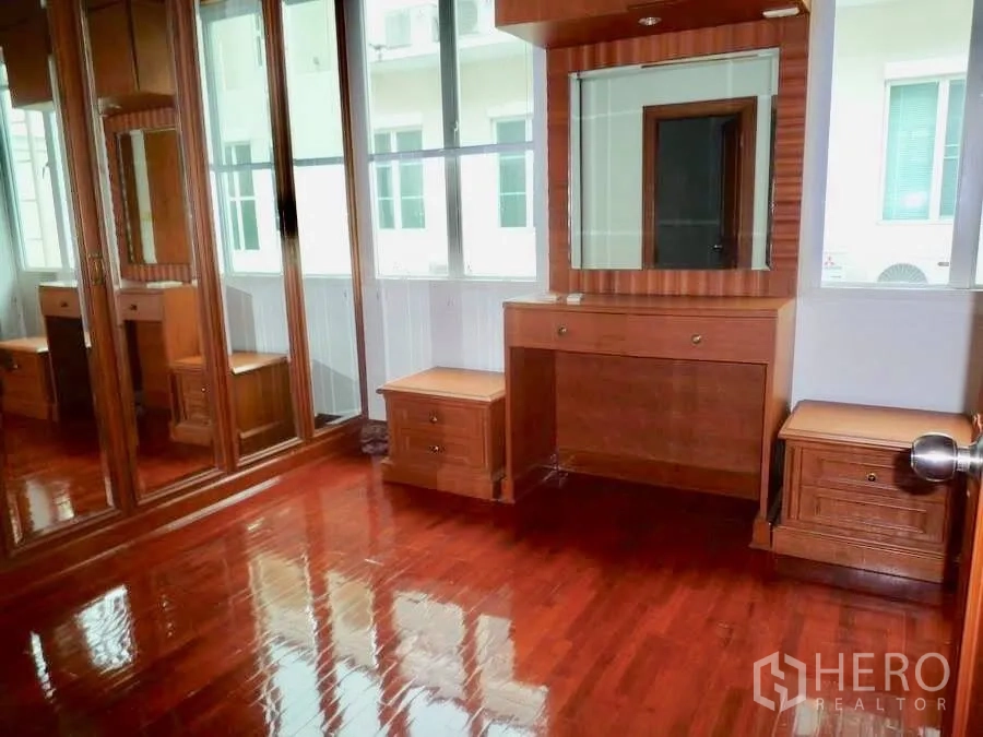 Townhouse for rent in Khlong Toei, Bangkok - Dressing room with mirrored wardrobes, vanity table and wood flooring.