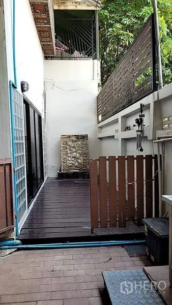 Detached House for rent - Side patio corridor with dark wood decking, privacy fence and a wall fountain.
