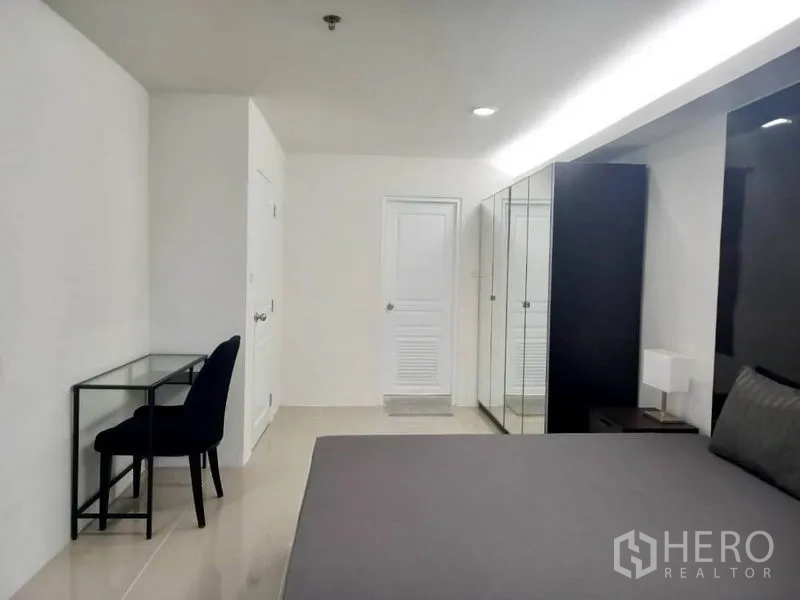 公寓 出租在Khlong Toei, Bangkok - 卧室一角设镜面衣柜与书桌，收纳与办公兼备。