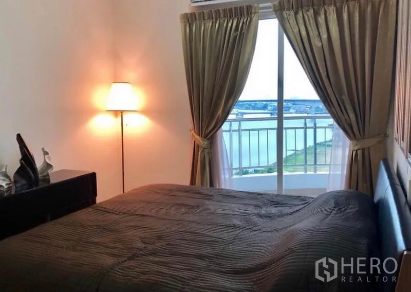 คอนโด ให้เช่าในBangkok - ห้องนอนมีผ้าม่านเต็มความสูง โคมไฟยืน และระเบียงชมวิวแม่น้ำ