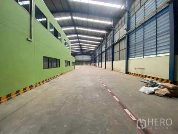 Warehouse for rent in Lat Lum Kaeo, Pathum Thani - Spacious warehouse interior with high steel roof and side office block with windows.