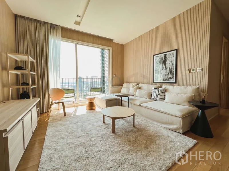 Condominium for sale in Khlong Toei, Bangkok - Living room opening to a balcony with seating and Sukhumvit city views.