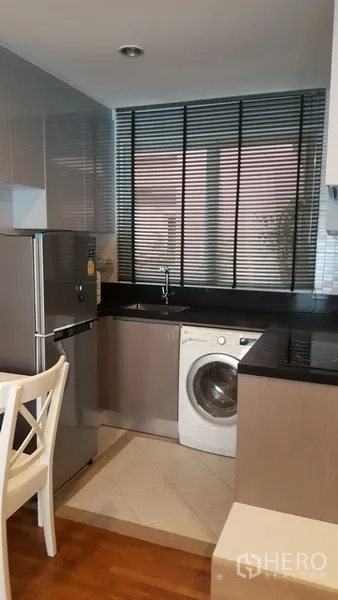 คอนโด ให้เช่าในWatthana, Bangkok - ครัวขนาดกะทัดรัด เคาน์เตอร์สีดำ มู่ลี่หน้าต่าง ตู้เย็นสเตนเลส และเครื่องซักผ้าฝาหน้า