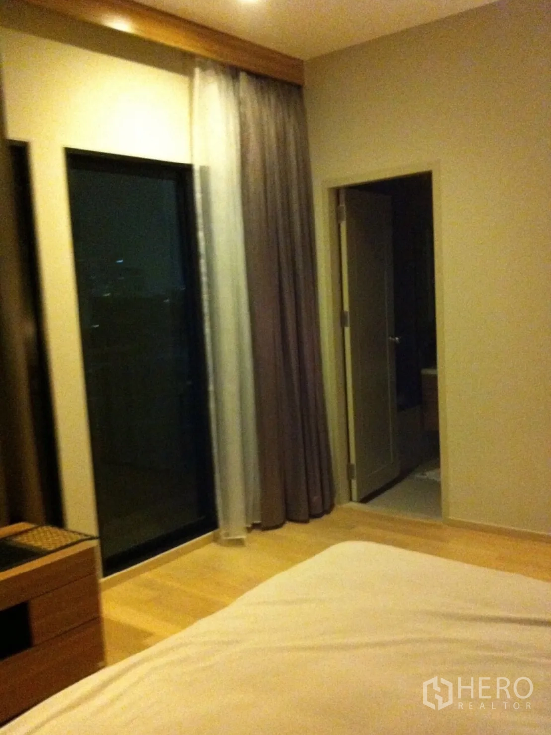 Condominium for rent or sale in Watthana, Bangkok - Bedroom with balcony access, floor-to-ceiling glass and door to en-suite bathroom.