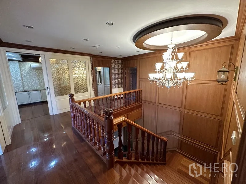 独立式住宅 出售在Lam Luk Ka, Pathum Thani - 木楼梯与吊灯的二层走廊 木质墙板装饰