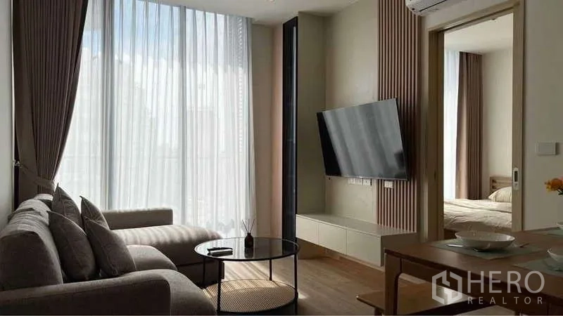 คอนโด ให้เช่าในWatthana, Bangkok - ห้องนั่งเล่นสว่างที่ Noble State 39 พร้อมโซฟาเข้ามุม ผ้าม่านสูงจรดเพดาน และทีวีติดผนัง เชื่อมสู่ห้องนอน