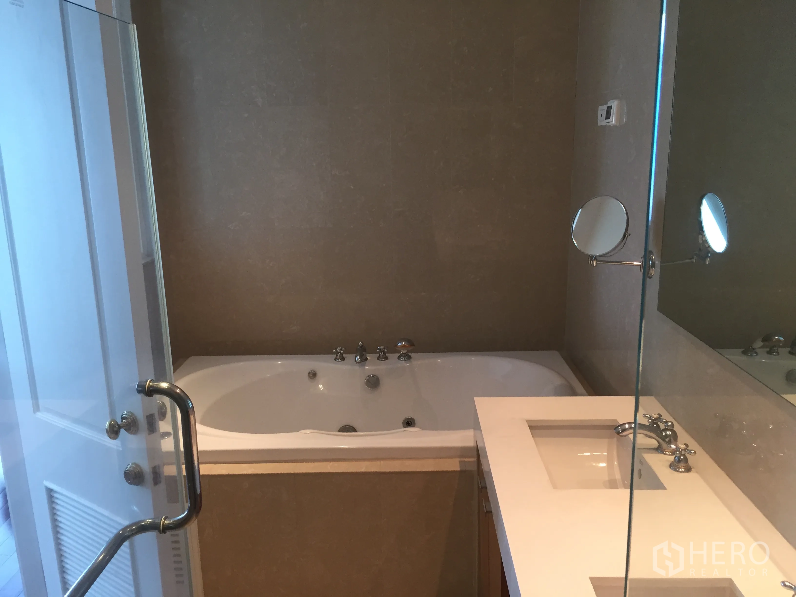Condominium for rent in Pathum Wan, Bangkok - Modern bathroom featuring a soaking bathtub, vanity counter and large wall mirror.