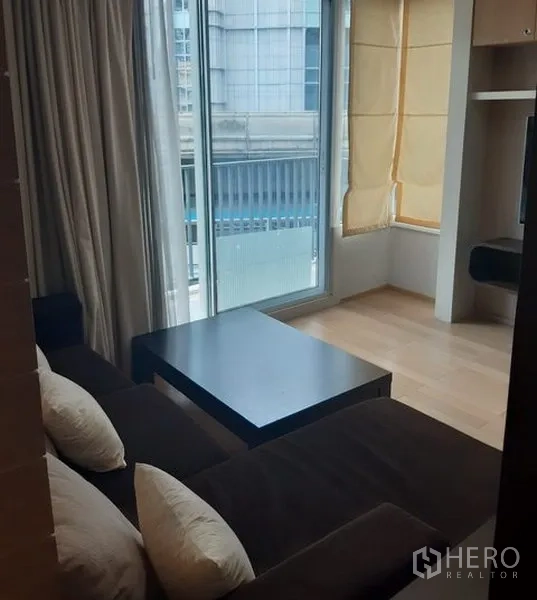 คอนโด ให้เช่าในKhlong Toei, Bangkok - ห้องนั่งเล่นมีหน้าต่างสูงจรดเพดาน โต๊ะกลาง และประตูสไลด์ออกระเบียง