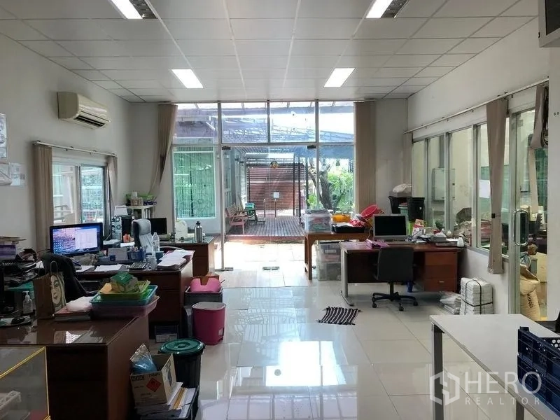 Factory for rent or sale in Khlong Luang, Pathum Thani - Bright administrative office with desks, glass wall and view to a garden patio.
