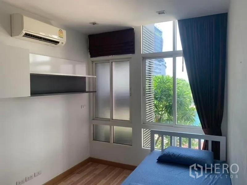 Condominium for rent or sale - Second bedroom with single bed, large corner windows and air conditioning.