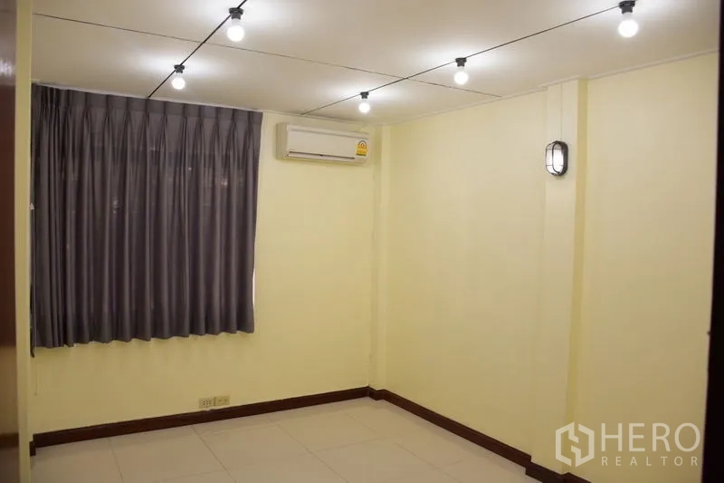 联排别墅 出租在Watthana, Bangkok - 空房间，灰色窗帘、分体空调与串灯。