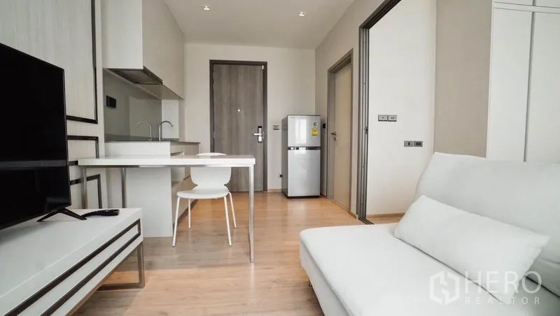 คอนโด ขายในKhlong Toei, Bangkok - มุมมองจากห้องนั่งเล่นไปยังครัวเล็ก โต๊ะทานอาหาร ชั้นวางทีวี และโถงทางเข้า