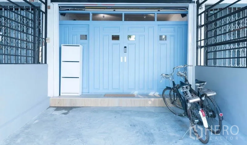 ทาวน์เฮาส์ ให้เช่าในKhlong Toei, Bangkok - ที่จอดรถในร่มพร้อมประตูนิรภัยสีฟ้าพาสเทล และจักรยานหน้าทาวน์เฮ้าส์