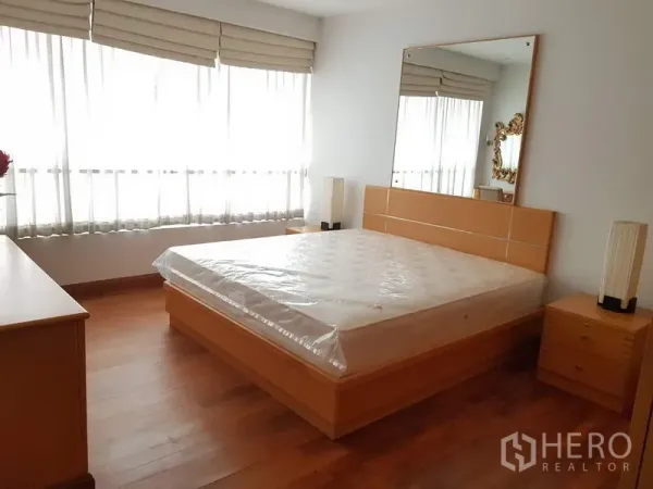 公寓 出租在Pathum Wan, Bangkok - 主卧配大窗、双人床、镜面床头与温暖木地板。