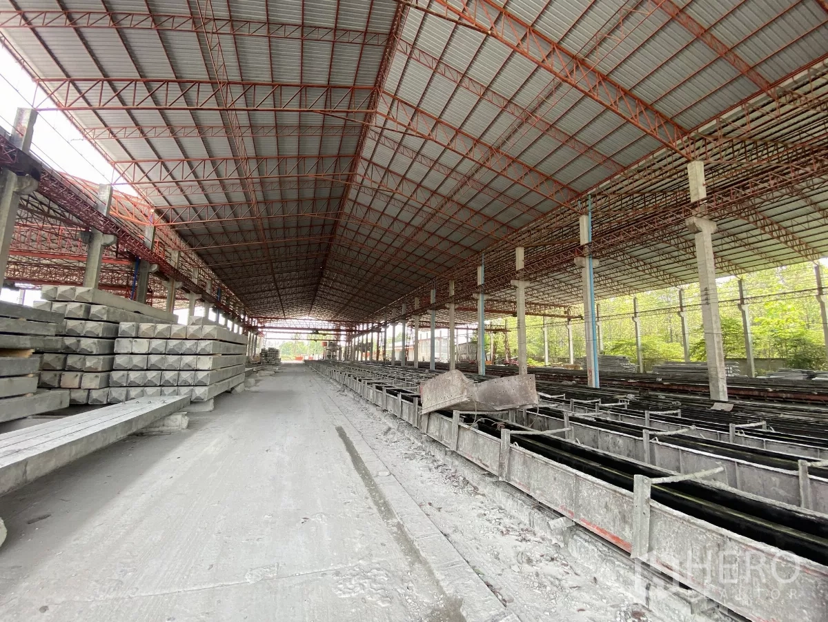 工厂 出售在Chon Buri - 穿越预制车间的长廊，两侧为模台与成品堆放。
