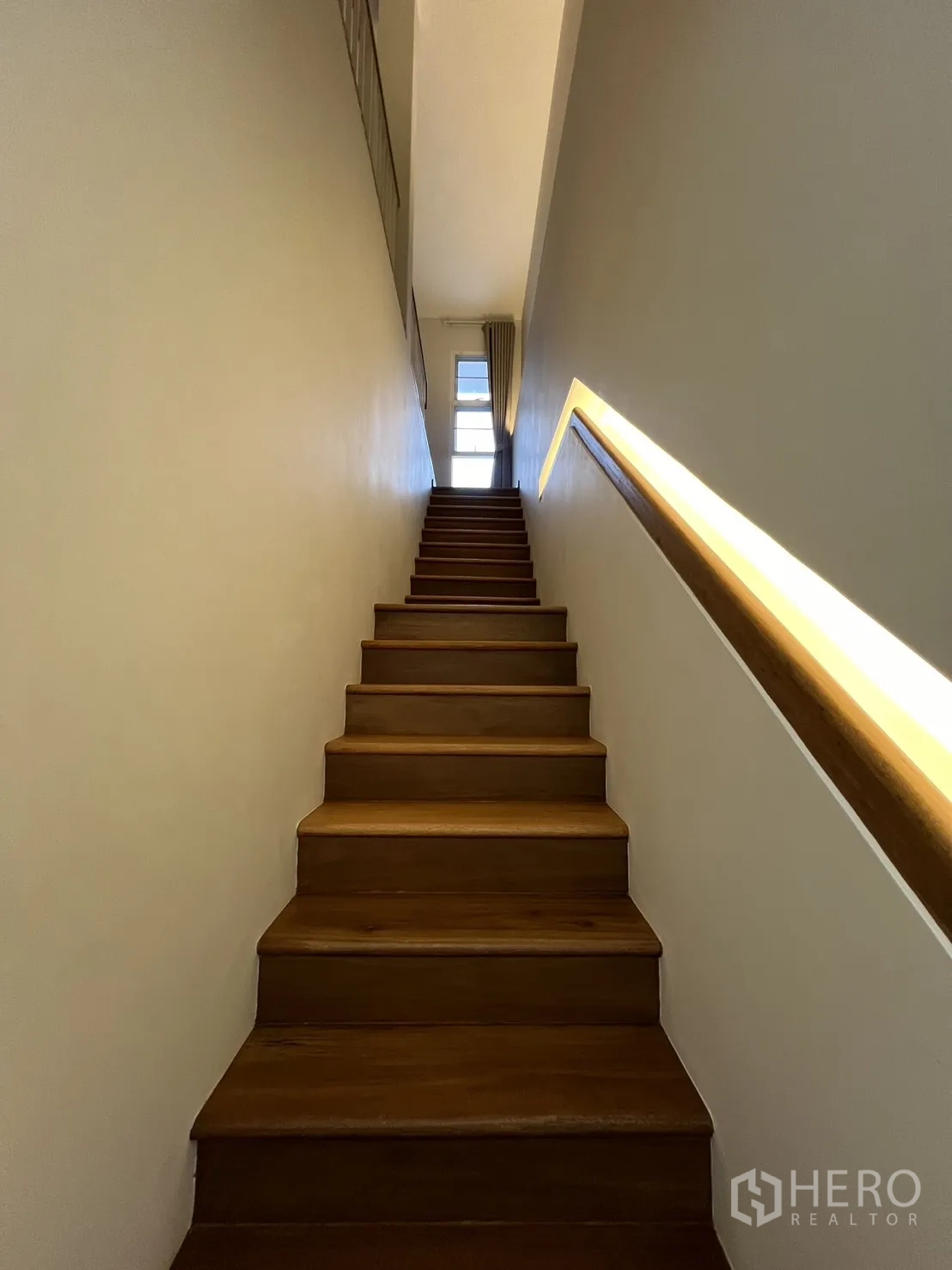 Detached House for rent in Saphan Sung, Bangkok - Wood staircase with warm LED handrail lighting and upper window.