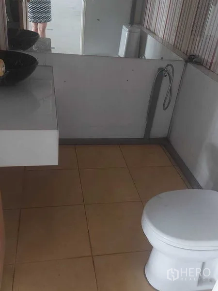 零售空间 出租在Pathum Wan, Bangkok - 卫生间，设坐便器、台上盆和镜子，地面为瓷砖。