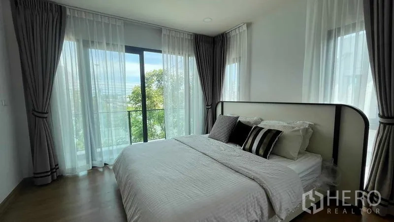 Detached House for rent in Bang Phli, Samut Prakan - Sunlit bedroom with large bed, sheer curtains and balcony overlooking greenery