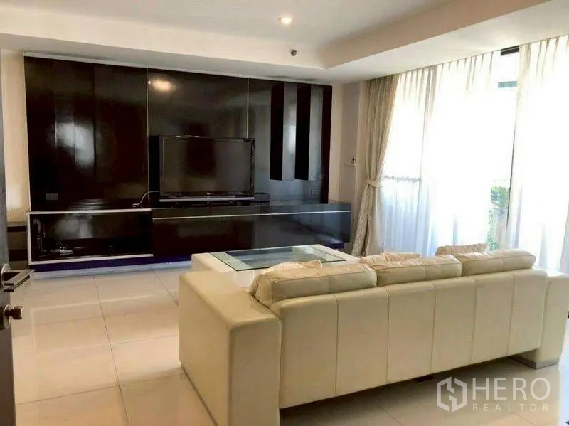 公寓 for rent or sale in Watthana, Bangkok - 客厅设电视背景墙、大型沙发与玻璃茶几。