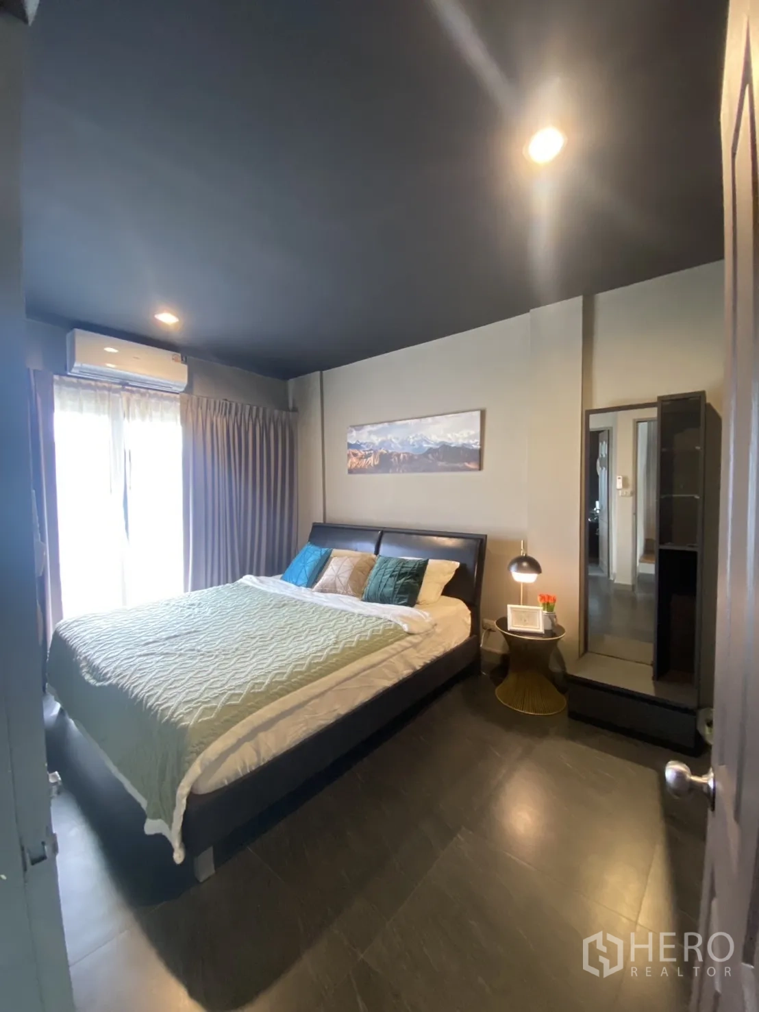 Townhouse for rent in Bang Kapi, Bangkok - Master bedroom angle with bedside lamp, tall mirror cabinet and curtains.