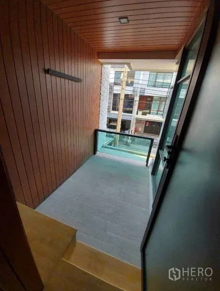 Townhouse for rent in Bang Phli, Samut Prakan - Covered balcony with wooden ceiling and glass railing overlooking neighboring townhomes.