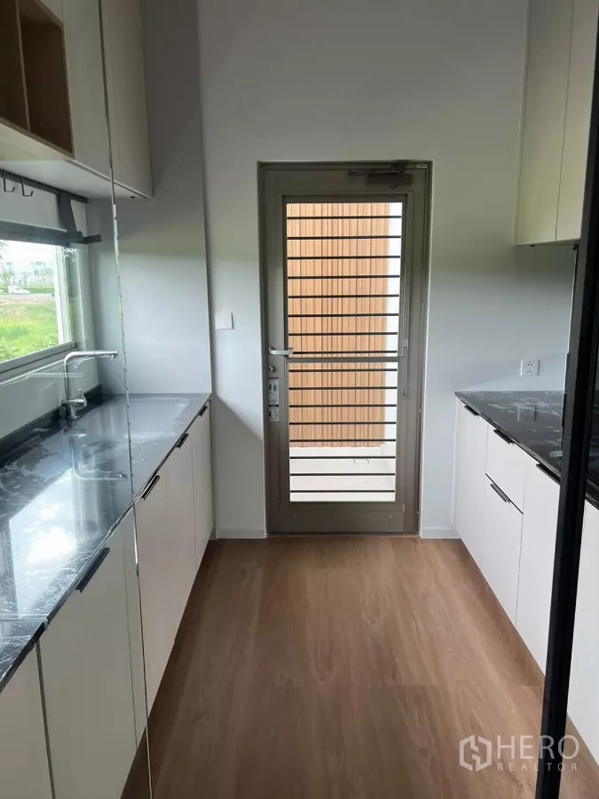 独立式住宅 出租在Saphan Sung, Bangkok - 备用走廊式厨房，双排橱柜与大理石纹台面，后门相连。