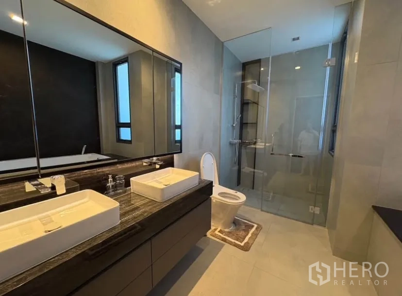 Detached House for rent in Suan Luang, Bangkok - En-suite bathroom with double vanity, glass shower enclosure and toilet.