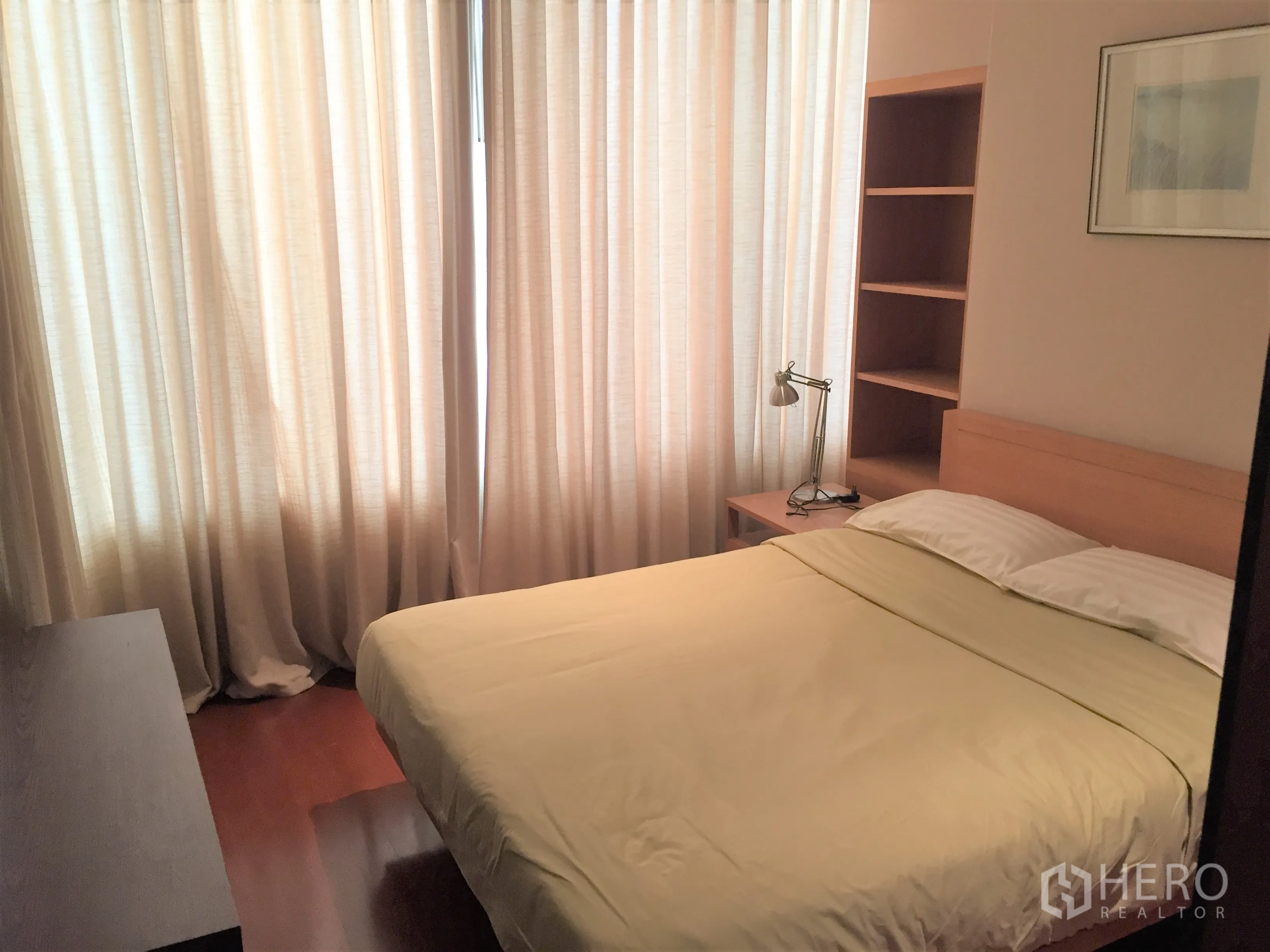 Condominium for rent in Bang Rak, Bangkok - Second bedroom with built-in shelving, desk lamp and full curtains around a double bed.