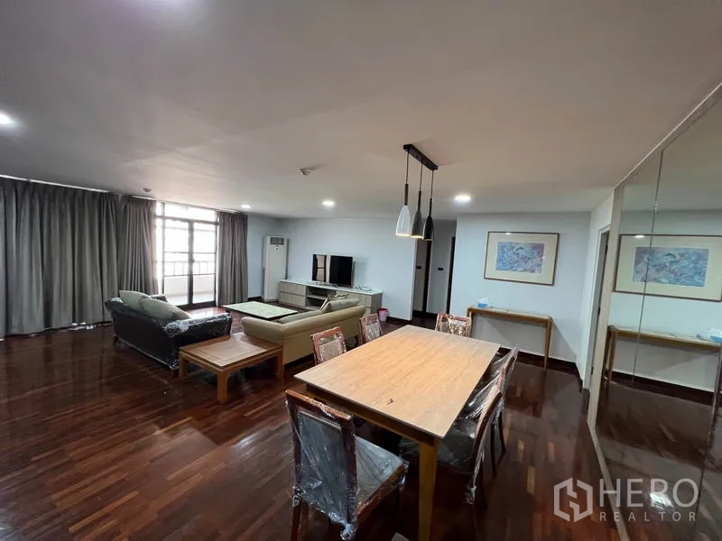 公寓 出租或出售在Watthana, Bangkok - 开阔客餐区，长餐桌，大窗与电视区。