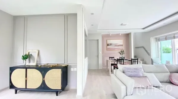 联排别墅 出租在Prawet, Bangkok - 开放式客餐厅，粉色装饰墙与L形沙发。