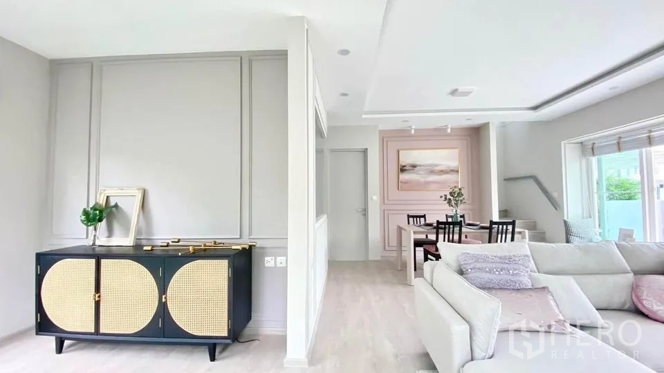 联排别墅 出租在Prawet, Bangkok - 开放式客餐厅，粉色装饰墙与L形沙发。