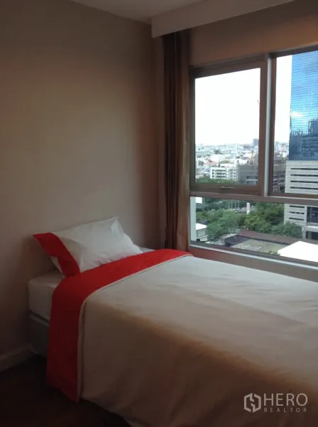 Condominium for rent in Huai Khwang, Bangkok - Bedroom with a single bed and large window capturing city views over the Rama 9 area.