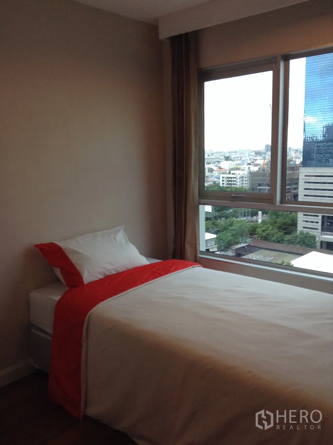 Condominium for rent in Huai Khwang, Bangkok - Bedroom with a single bed and large window capturing city views over the Rama 9 area.