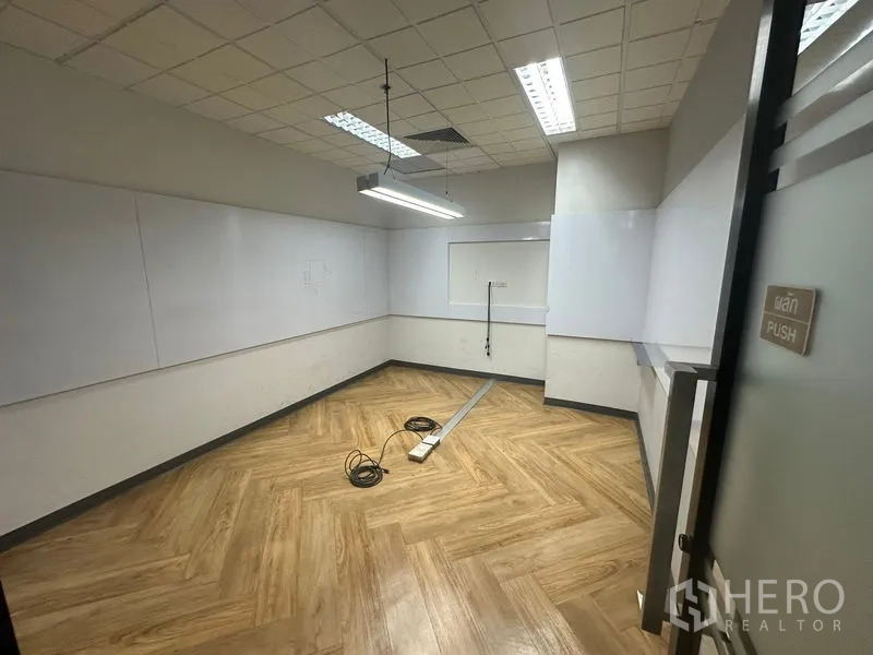 Office Space for rent - Compact meeting room with wall whiteboards, herringbone floor and a suspended linear light.