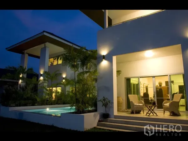 บ้าน ให้เช่าในKhan Na Yao, Bangkok - เฉลียงมีหลังคาพร้อมชุดเก้าอี้หวาย ข้างสระว่ายน้ำและประตูกระจกบานเลื่อนสู่ห้องนั่งเล่น