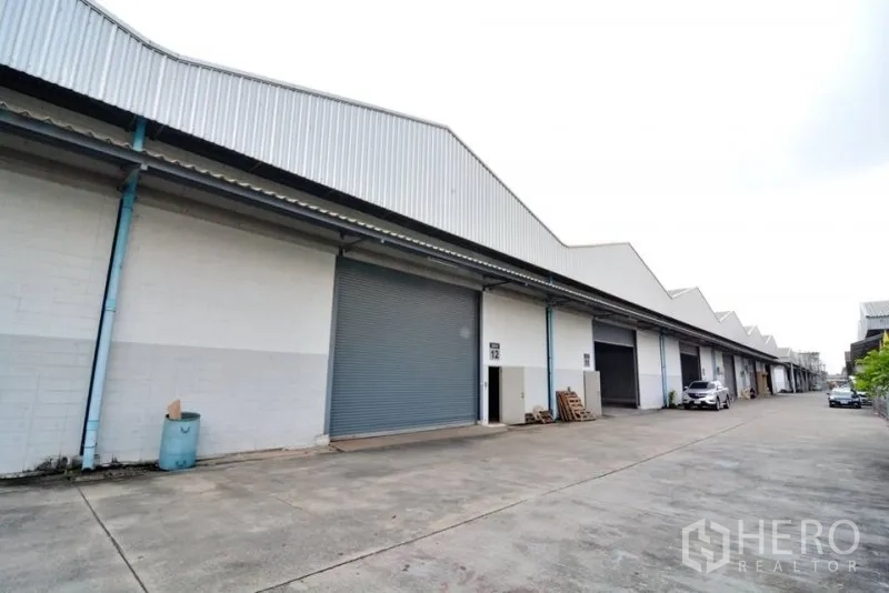 货栈 出租在Phra Pradaeng, Samut Prakan - 仓库外立面，卷闸门与宽阔通道，适合卡车出入。