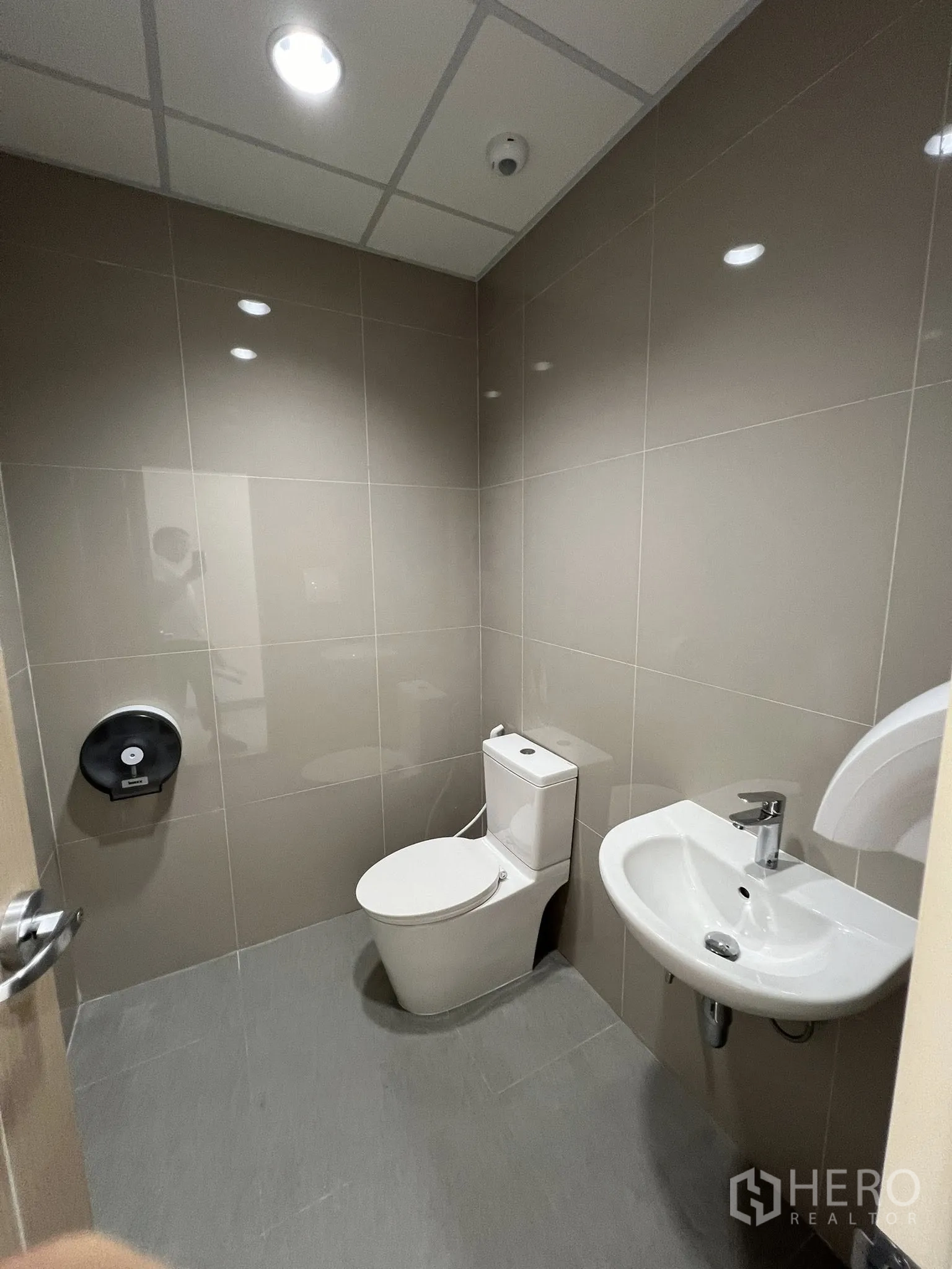 Warehouse for rent in Phra Pradaeng, Samut Prakan - Clean restroom with a toilet, sink and tiled walls and ceiling lighting.