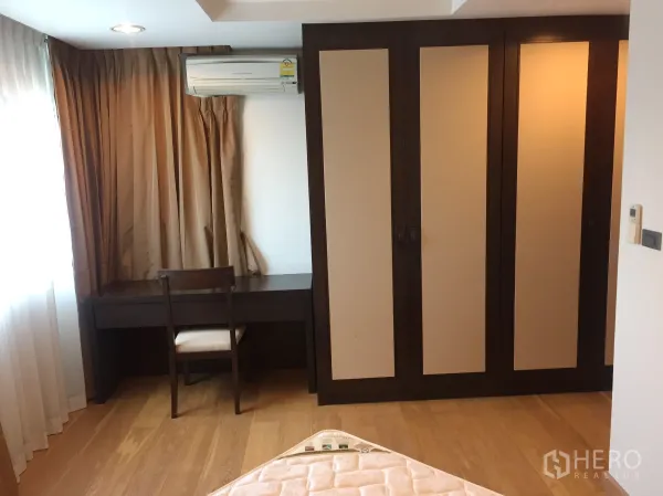 Condominium for rent in Sathon, Bangkok - Second bedroom featuring a large wardrobe, study desk by the window and warm wood flooring.