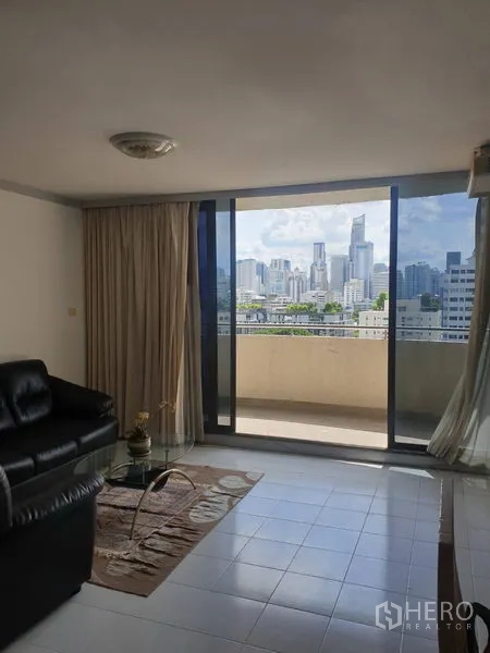 Condominium for rent in Watthana, Bangkok - Living room with sliding glass doors opening to a balcony and skyline view of Bangkok.