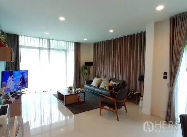 Detached House for rent in Bang Kapi, Bangkok - Bright living room with floor-to-ceiling windows, recessed lighting, sofa and TV unit.