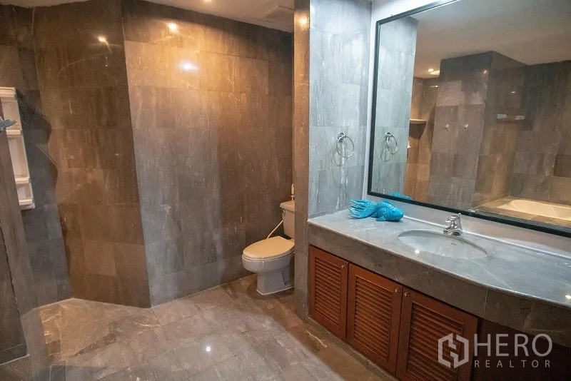 อพาร์ทเมนท์ ให้เช่าในWatthana, Bangkok - เคาน์เตอร์อ่างล้างหน้า กระจกบานใหญ่ ตู้เก็บของ และโถสุขภัณฑ์ โทนหินสีเทา.