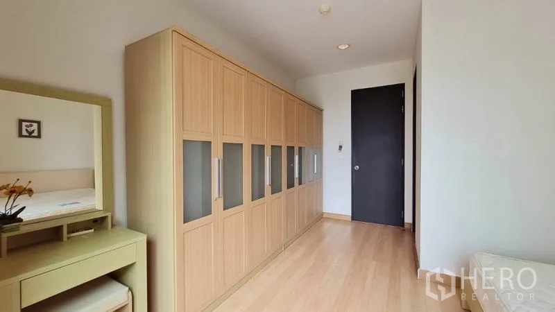 Condominium for rent in Khlong Toei, Bangkok - Bedroom corridor featuring a wall of fitted wardrobes and a dressing table.