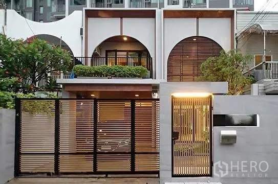 Townhouse for rent in Watthana, Bangkok - Front gate and facade of townhouse with slatted fence and warm lighting.