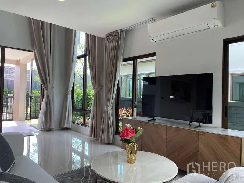 Detached House for rent in Bang Kapi, Bangkok - Living area opening to covered terrace, featuring TV cabinet and ample glazing.