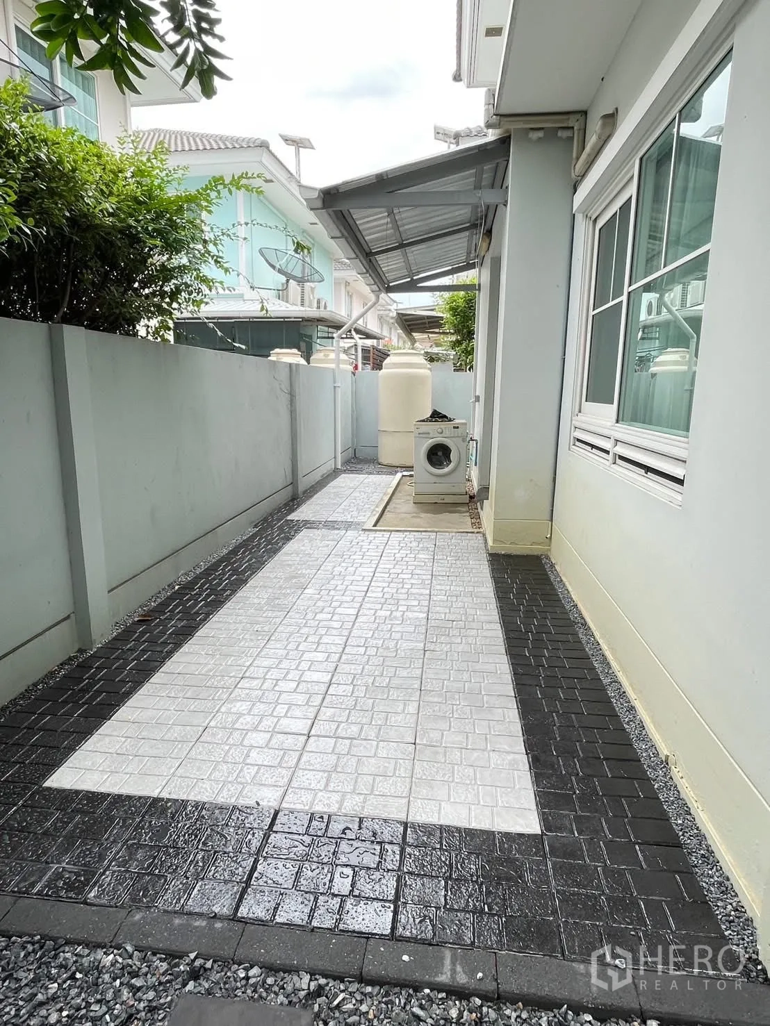 Detached House for rent in Bang Phli, Samut Prakan - Side yard with patterned tiles, awning roof and washing machine.
