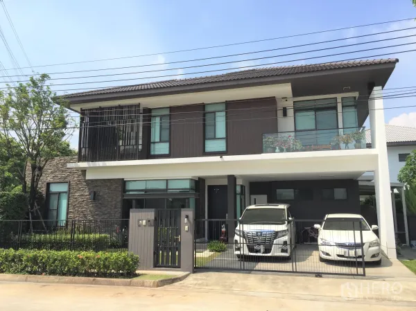 Detached House for rent or sale in Prawet, Bangkok - Modern two-storey detached house with stone accents, balcony and gated two-car carport.